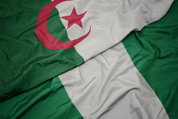 Ondeando colorida bandera de nigeria y bandera nacional de algeria . —  Fotos de Stock