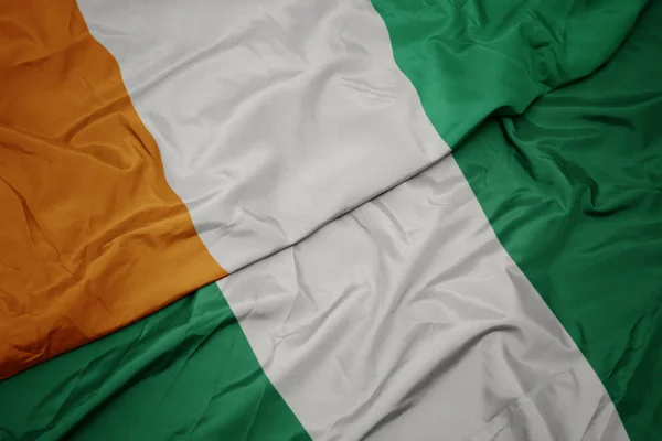 Schwenken bunte Flagge Nigerias und Nationalflagge der Cote divoire. — Stockfoto