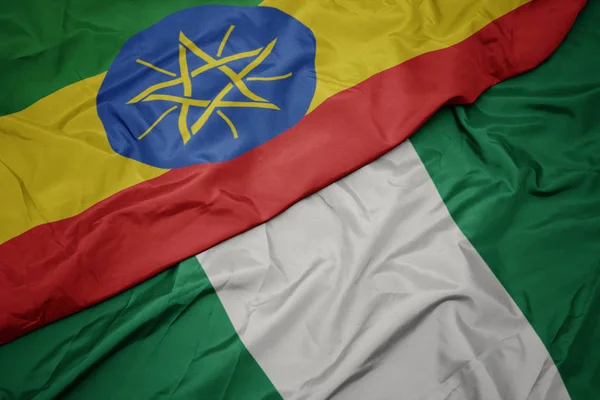 Mávání barevnou vlajkou Nigérie a národní vlajky etiopie . — Stock fotografie