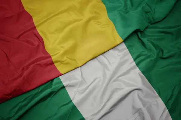 Waving colorful flag of nigeria and national flag of guinea. — Stock Photo, Image