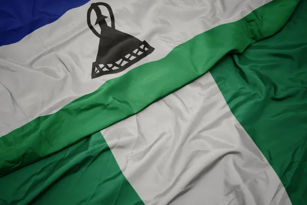 Agitant drapeau coloré du Nigéria et drapeau national du Lesotho . — Photo