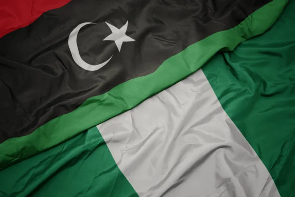 Waving colorful flag of nigeria and national flag of libya. — Stock Photo, Image