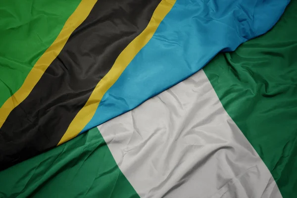 Ondeando colorida bandera de nigeria y bandera nacional de tanzania . —  Fotos de Stock