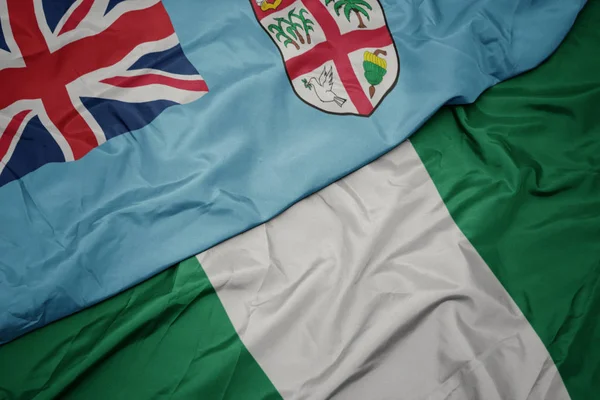 Waving colorful flag of nigeria and national flag of Fiji . — Stock Photo, Image