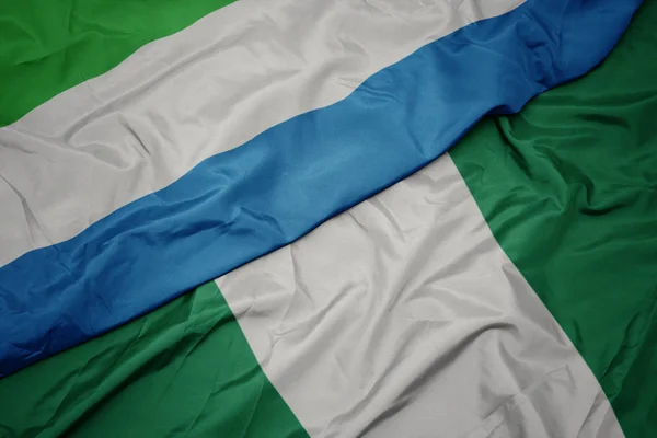 Sventolando bandiera colorata della Nigeria e bandiera nazionale della sierra leone . — Foto Stock