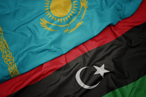 Ondeando colorida bandera de libya y bandera nacional de kazakhstan . — Foto de Stock