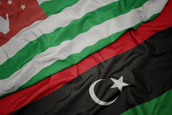 Waving colorful flag of libya and national flag of abkhazia. — Stock Photo, Image