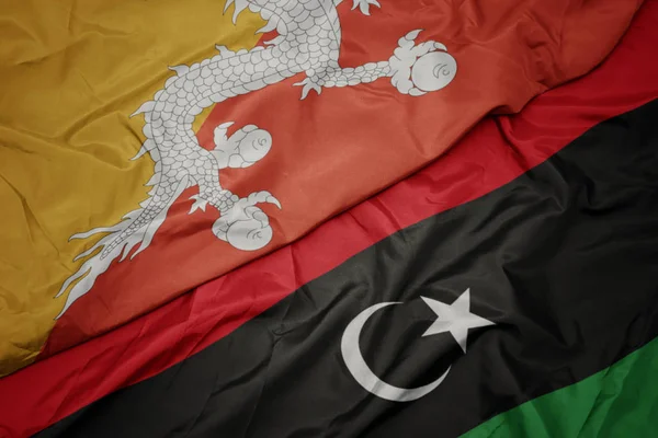 Ondeando colorida bandera de libya y bandera nacional de Bután . — Foto de Stock