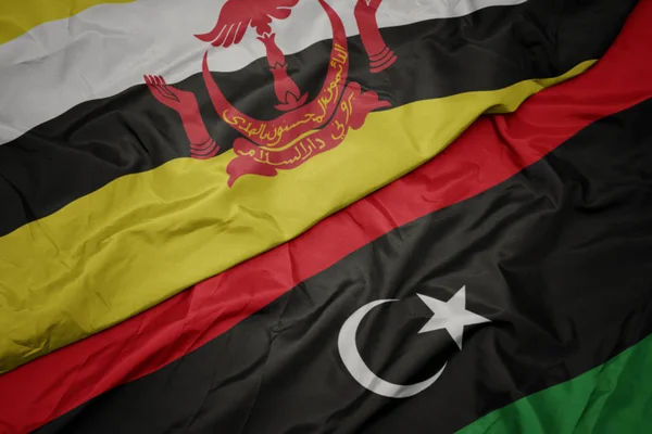 Ondeando colorida bandera de libya y bandera nacional de brunei . — Foto de Stock