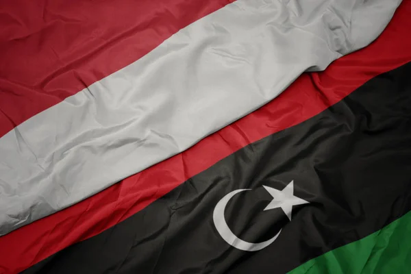 Waving colorful flag of libya and national flag of indonesia. — Stock Photo, Image