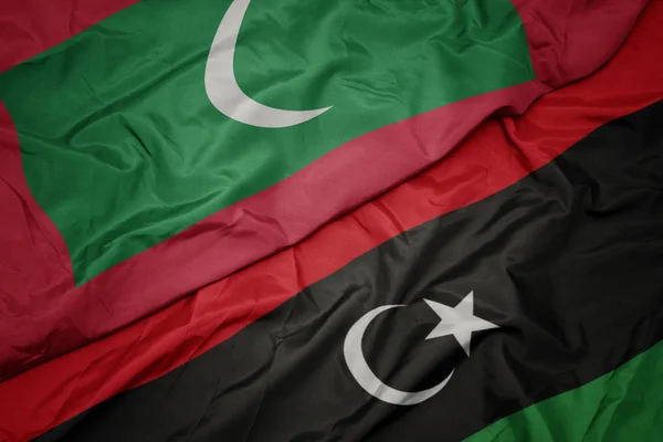 Waving colorful flag of libya and national flag of maldives. — Stock Photo, Image