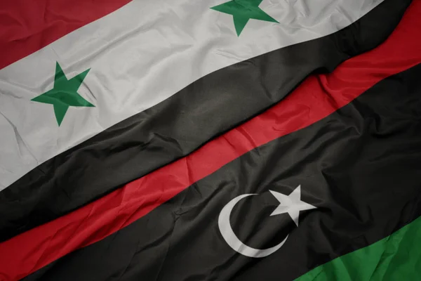 Waving colorful flag of libya and national flag of syria. — Stock Photo, Image