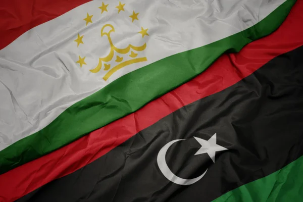 Waving colorful flag of libya and national flag of tajikistan. — Stock Photo, Image
