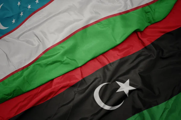Ondeando colorida bandera de libya y bandera nacional de Uzbekistán . — Foto de Stock