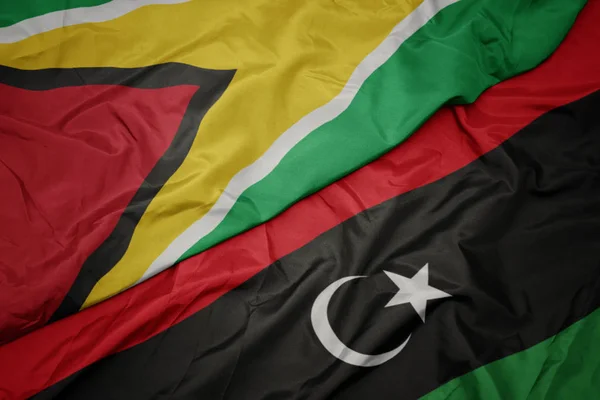 Agitant le drapeau coloré de la libya et le drapeau national du Guyana . — Photo