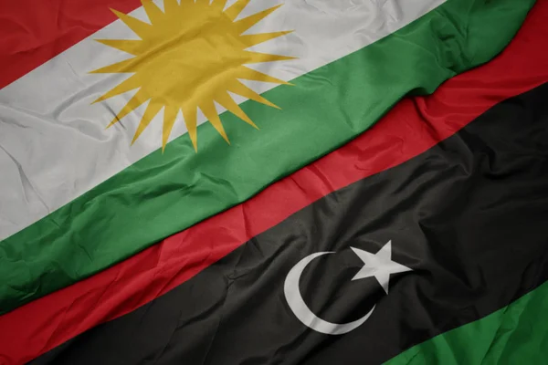 Zwaaiende vlag van Libië en nationale vlag van Kurdistan. — Stockfoto