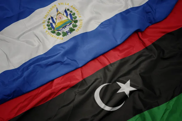 Acenando bandeira colorida da Líbia e bandeira nacional de el salvador . — Fotografia de Stock