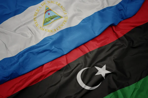 Acenando bandeira colorida da Líbia e bandeira nacional da nicarágua . — Fotografia de Stock