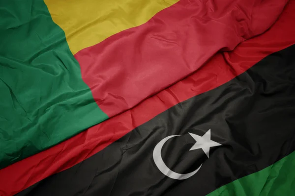 Ondeando colorida bandera de libya y bandera nacional de benin . — Foto de Stock