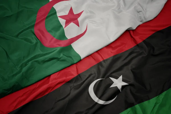 Waving colorful flag of libya and national flag of algeria. — Stock Photo, Image