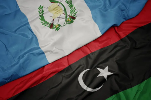 Acenando bandeira colorida da Líbia e bandeira nacional de guatemala . — Fotografia de Stock