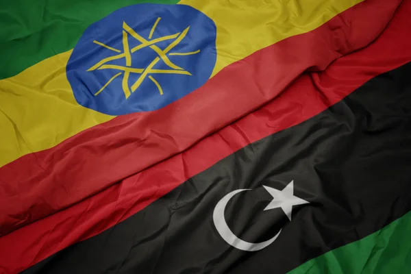 Ondeando colorida bandera de libya y bandera nacional de ethiopia  . — Foto de Stock