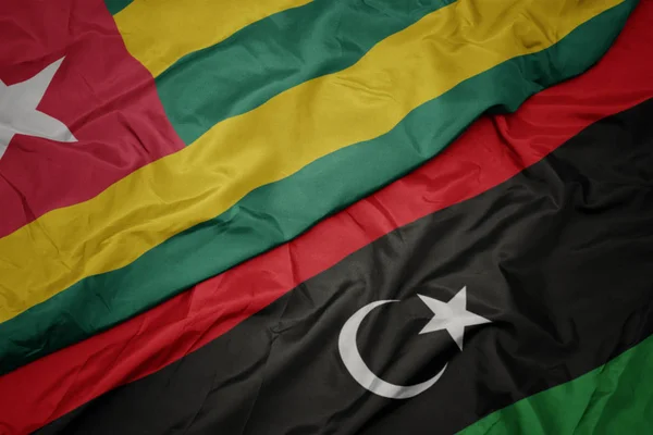 Ondeando colorida bandera de libya y bandera nacional de togo . — Foto de Stock