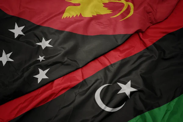 Schwenken bunte libysche Flagge und Nationalflagge von Papua Neuguinea . — Stockfoto