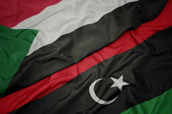 Waving colorful flag of libya and national flag of sudan. — Stock Photo, Image