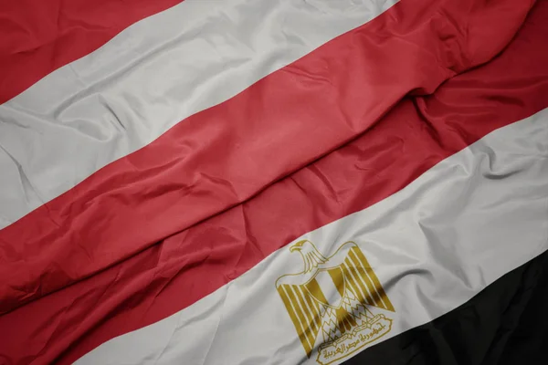 Mávající barevnou vlajkou Egypta a státní vlajkou Rakouska. — Stock fotografie