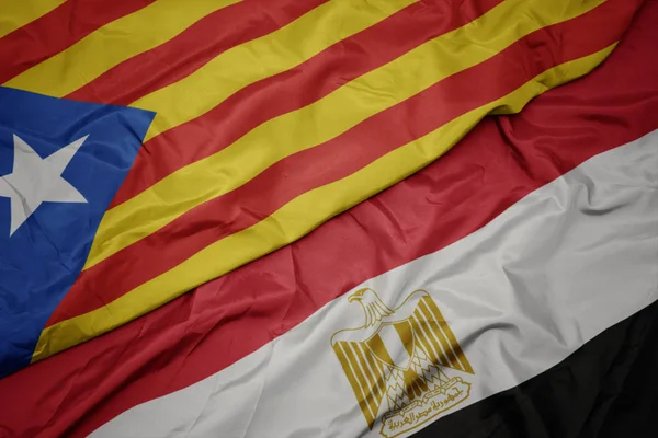 Agitant drapeau coloré de l'Egypte et drapeau national de la catalonie . — Photo