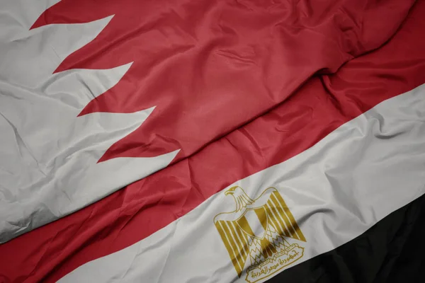 waving colorful flag of egypt and national flag of bahrain.