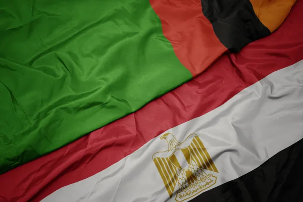 waving colorful flag of egypt and national flag of zambia.