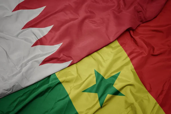 waving colorful flag of senegal and national flag of bahrain.