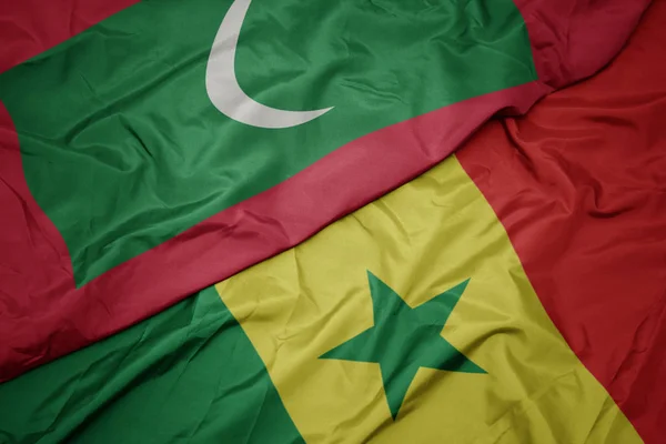 Schwenken bunte Flagge des Senegal und Nationalflagge der Malediven. — Stockfoto