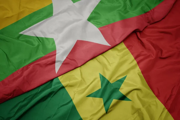 Ondeando colorida bandera de senegal y bandera nacional de myanmar . — Foto de Stock