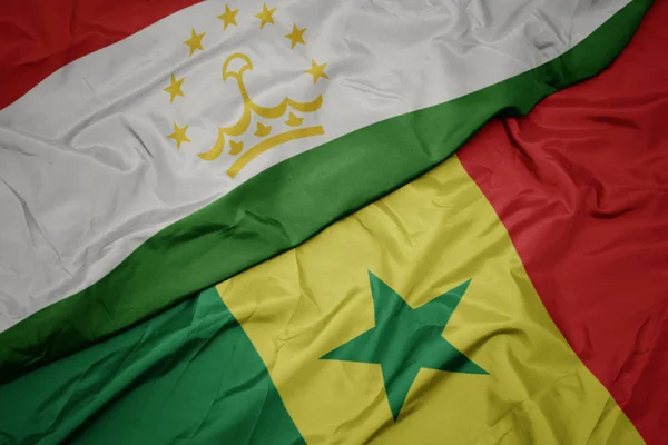 Ondeando colorida bandera de senegal y bandera nacional de Tayikistán . — Foto de Stock