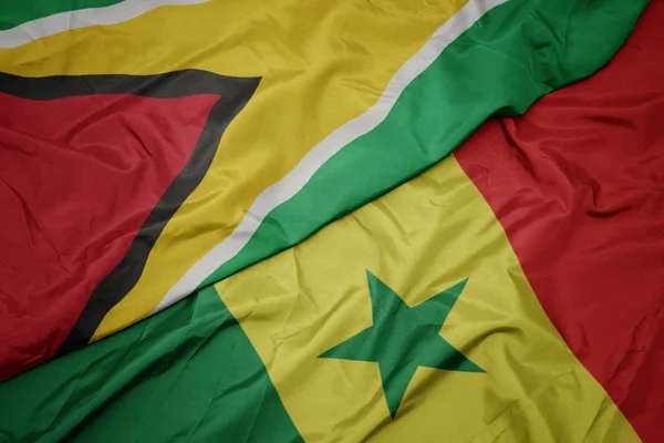 Machanie barwną flagą senegalu i flagą narodową Gujany. — Zdjęcie stockowe