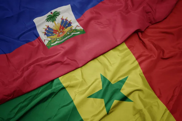 Zwaaiende kleurrijke vlag van senegal en nationale vlag van Haïti. — Stockfoto