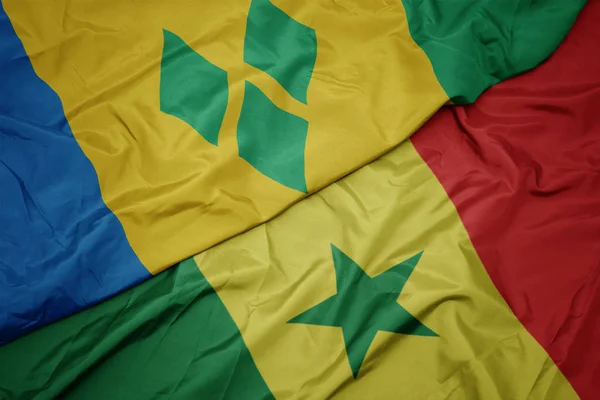 Waving colorful flag of senegal and national flag of saint vincent and the grenadines. — ストック写真