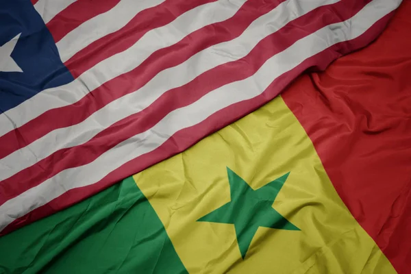 Waving colorful flag of senegal and national flag of liberia. — Stock Photo, Image