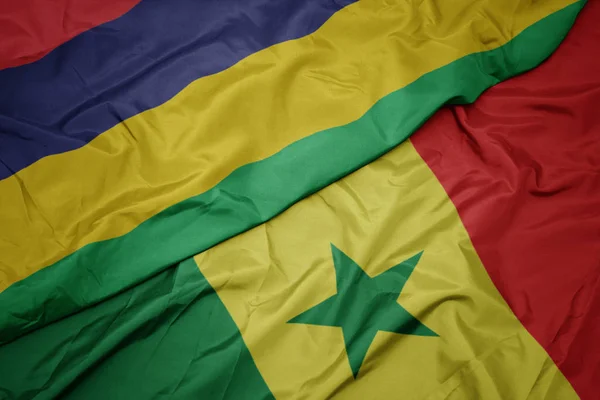 Machanie kolorową flagą senegalu i flagą narodową Mauritiusa. — Zdjęcie stockowe