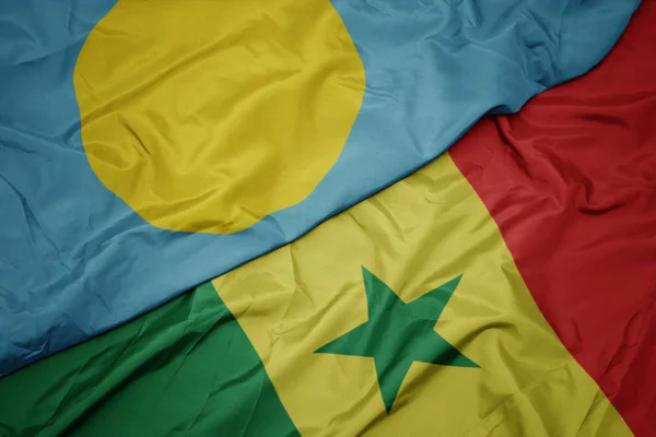 Waving colorful flag of senegal and national flag of Palau . — Stock Photo, Image