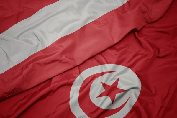 waving colorful flag of tunisia and national flag of austria.