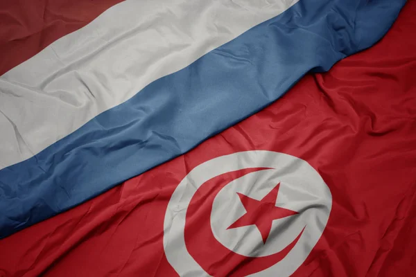 Waving colorful flag of tunisia and national flag of luxembourg. — Stock Photo, Image