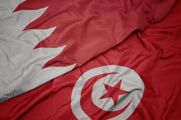 waving colorful flag of tunisia and national flag of bahrain.