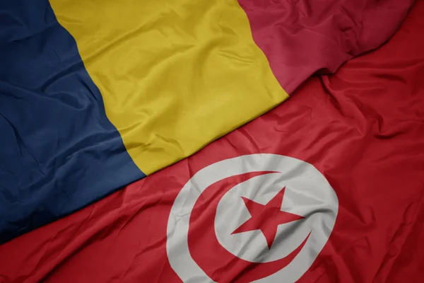waving colorful flag of tunisia and national flag of chad.