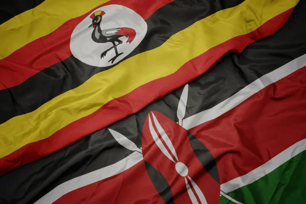 Sventolando bandiera colorata di kenya e bandiera nazionale di uganda . — Foto Stock