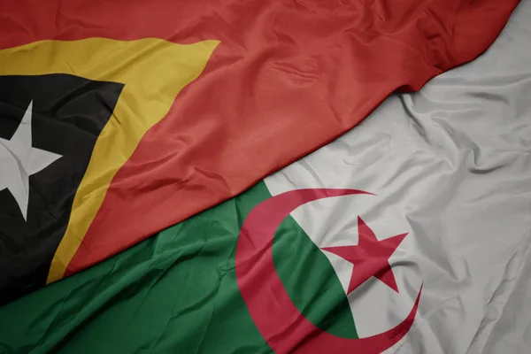 アルジェリアのカラフルな旗と東ティモールの国旗を振って. — ストック写真
