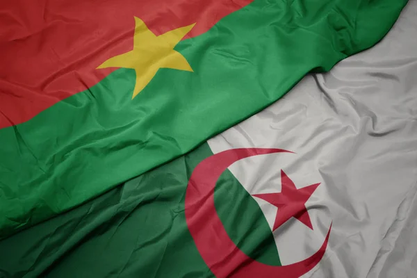 Schwenken bunte algerische Flagge und Nationalflagge der Burkina Faso. — Stockfoto